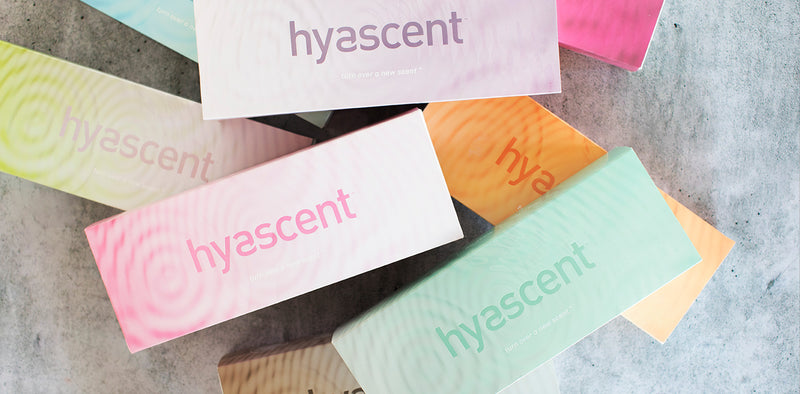 Overhead photograph of Hyascent Fragrance Diffuser packaging boxes stacked on top of each other in an organic way. The packages are in many different bright and pastel colors.